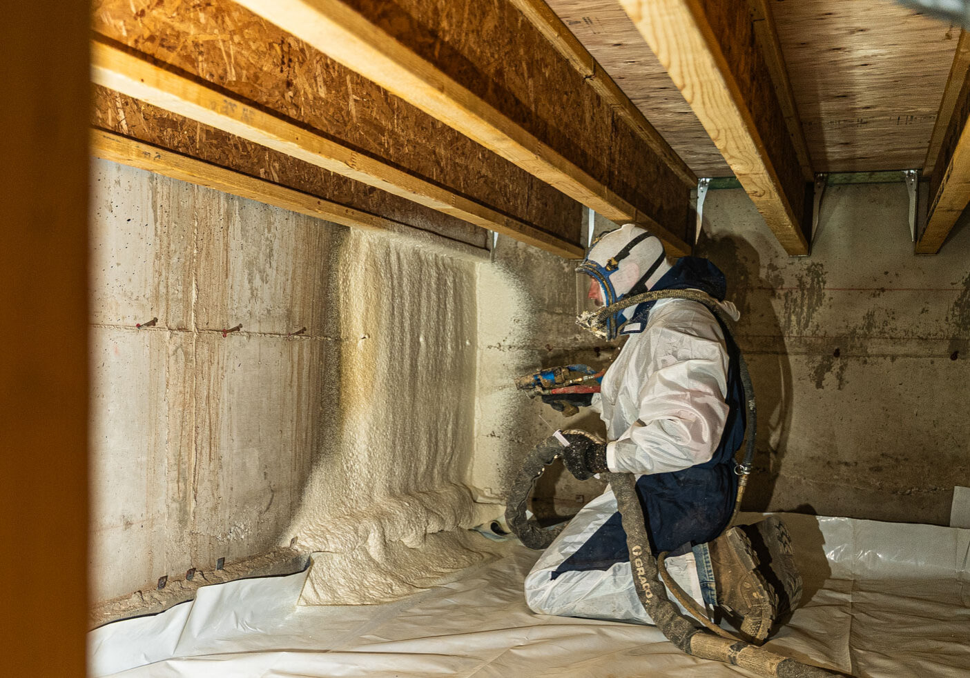509_Spray_Foam_crawlspace_001 Worker applying insulation foam in crawl space.