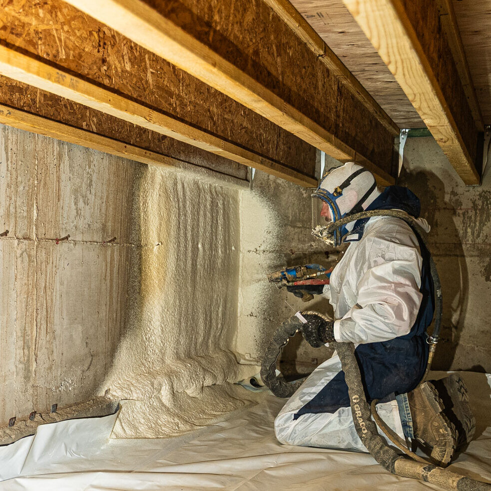509_Spray_Foam_crawlspace_001 Worker applies spray foam insulation in crawlspace.