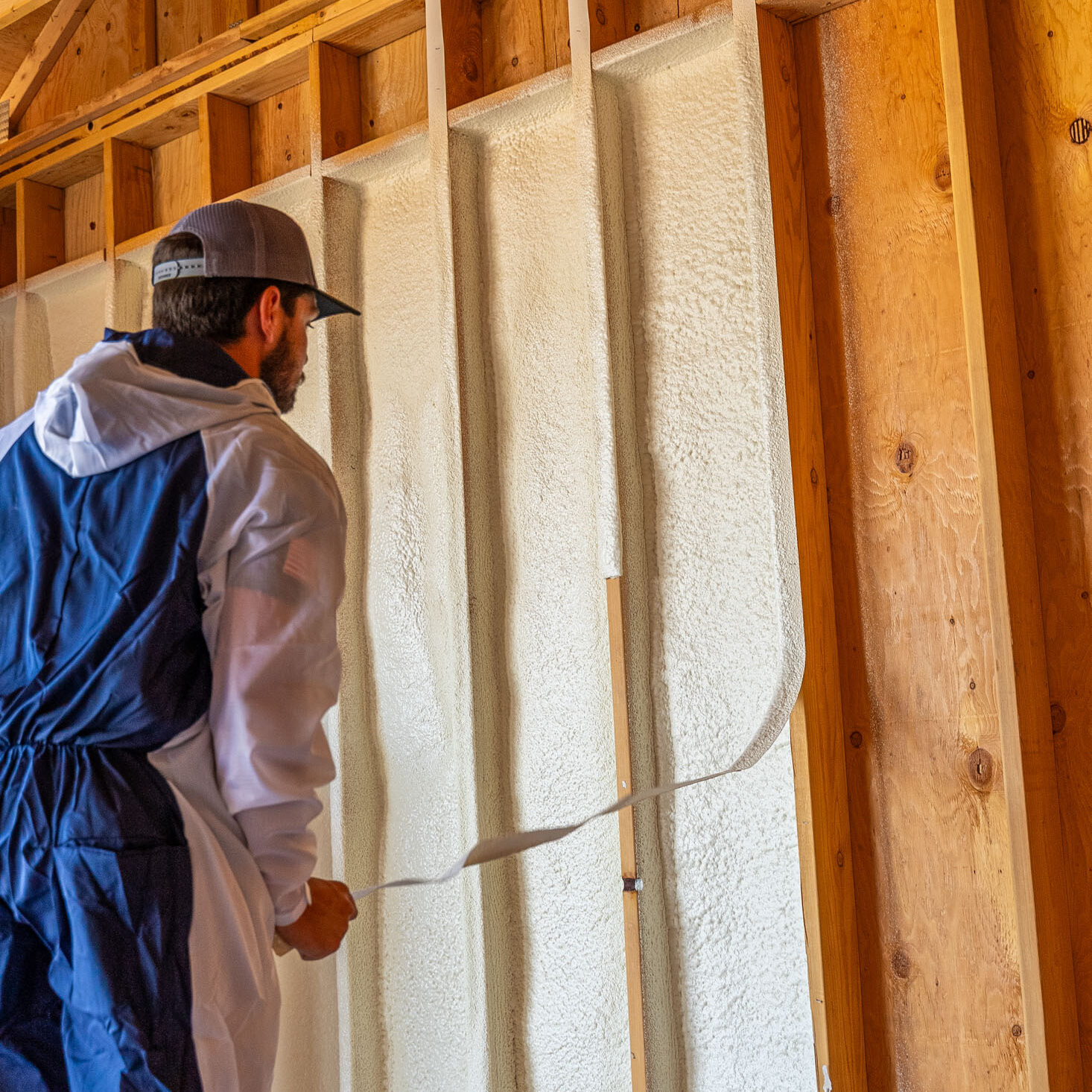 509_Spray_Foam_insulation_030 Worker installing spray foam insulation on wooden wall.