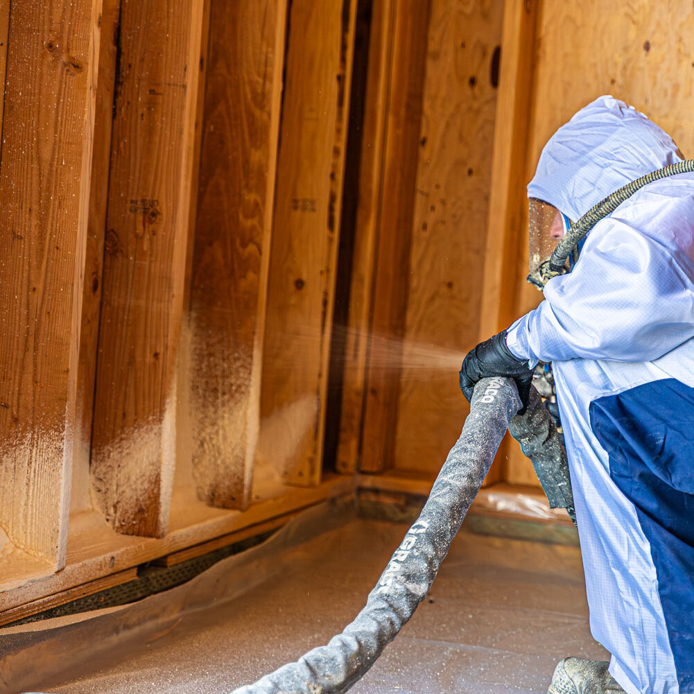 509_Spray_Foam_insulation_051 Worker applying spray foam insulation to wooden wall.